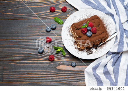 portion of Classic tiramisu dessert with raspberries and blueberries on wooden background portion of Classic tiramisu dessert with raspberries and blueberries on wooden background 69541602