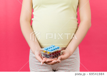 Close up of heap of blisters of pills in pregnant woman's hand at colorful background with copy space. Healthcare and treatment during pregnancy concept Close up of heap of blisters of pills in pregnant woman's hand at colorful background with copy space. Healthcare and treatment during pregnancy concept 69541984