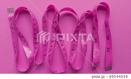 Pink centimeter on pink background. Simple flat lay with pastel texture. Fitness concept. Stock photo. 69544039