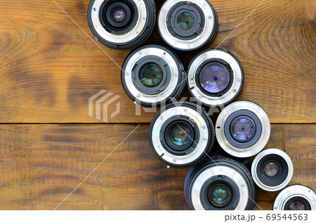 Several photographic lenses lie on a brown wooden background. Sp Several photographic lenses lie on a brown wooden background. Sp 69544563