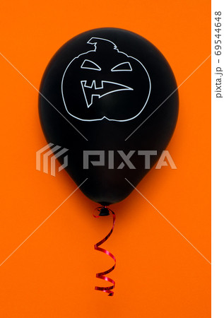 Black balloon on orange background with scary face. Halloween decoration. Black balloon on orange background with scary face. Halloween decoration. 69544648
