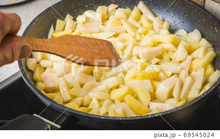 A woman frying potatoes in the kitchen A woman frying potatoes in the kitchen 69545024