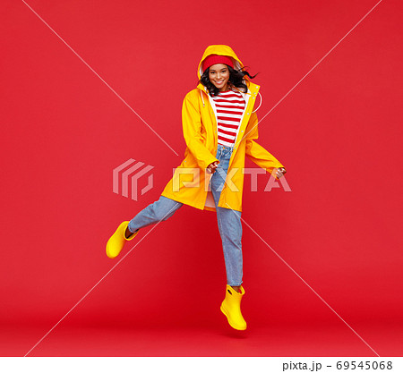 Happy ethnic autumn female jumping on red background Happy ethnic autumn female jumping on red background 69545068
