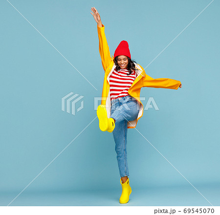 Happy ethnic female in autumn in raincoat and boots 69545070