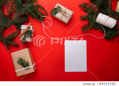 Christmas red background with fit tree branches , gifts and white card Christmas red background with fit tree branches , gifts and white card 69545281