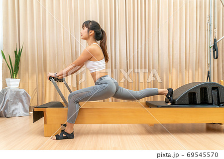 Young Asian woman working on pilates reformer machine during her Young Asian woman working on pilates reformer machine during her 69545570