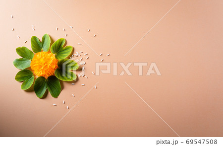 Happy Dussehra. Yellow flowers, green leaf and rice on orange pa 69547508