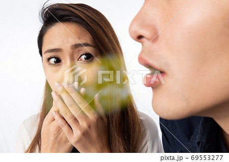 男性の口臭に口を塞ぐ女性 69553277