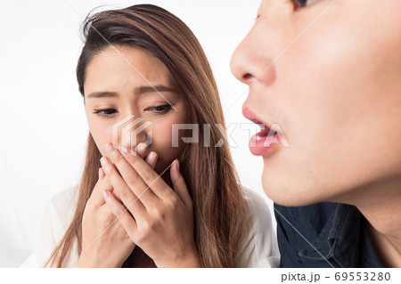 男性の口臭に口を塞ぐ女性 69553280