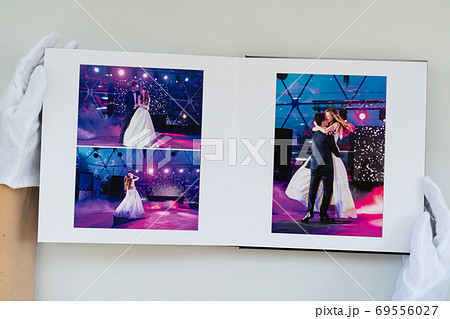 hands in white gloves flipping through photo book  69556027