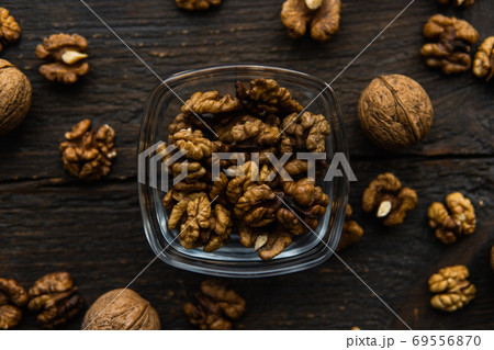 Walnut in a smale plate with scattered shelled nuts and whole nut which standing on a wooden vintage table. Walnuts is a healthy vegetarian protein nutritious food. Walnut on rustic old wood. 69556870