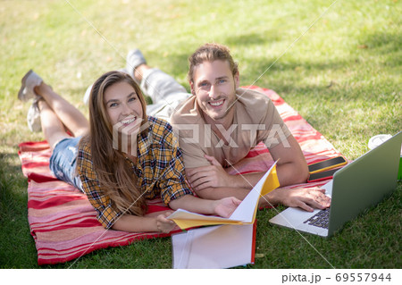 Young happy couple lying on the grass and studying 69557944