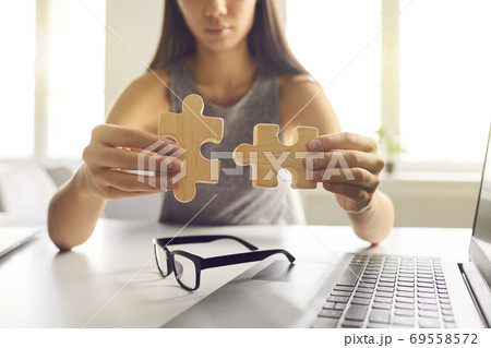 Close-up of businesswoman joining two pieces of jigsaw puzzle as metaphor for finding solution 69558572