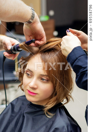 Hairdresser curling long light brown hair Hairdresser curling long light brown hair 69558796