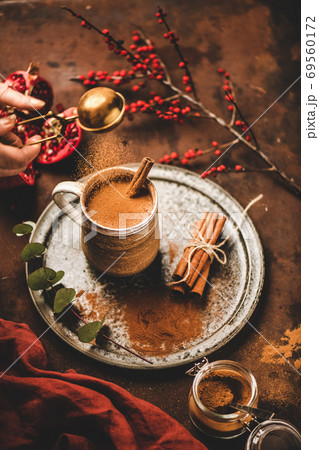 Human hand pouring cinnamon to turkish hot drink 69560172