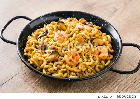 Traditional Spanish fideua. Noodle paella on wooden table Traditional Spanish fideua. Noodle paella on wooden table 69561918