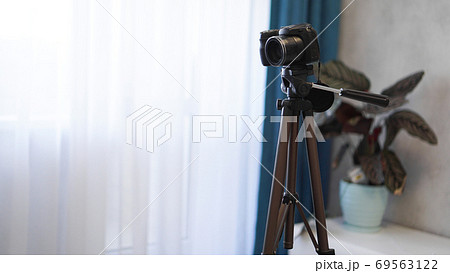 Camera on a tripod indoors. Filming a video blog or photographing at home Camera on a tripod indoors. Filming a video blog or photographing at home 69563122