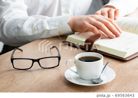 Man in white shirt reading notes in notebook Man in white shirt reading notes in notebook 69563643