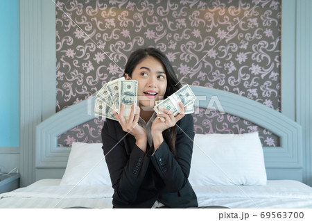Rich business Asian Thai woman counting money to save banknote in financial account and investment concept on bed in bedroom in hotel. Rich business Asian Thai woman counting money to save banknote in financial account and investment concept on bed in bedroom in hotel. 69563700