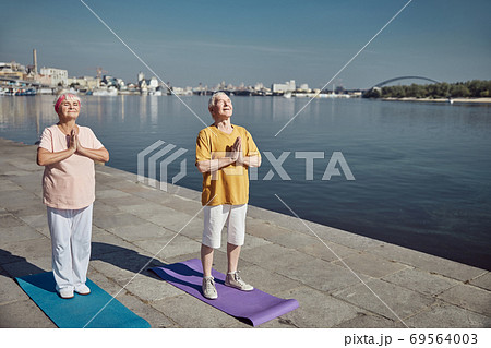 Pensioners meditating in a prayer pose outdoors Pensioners meditating in a prayer pose outdoors 69564003