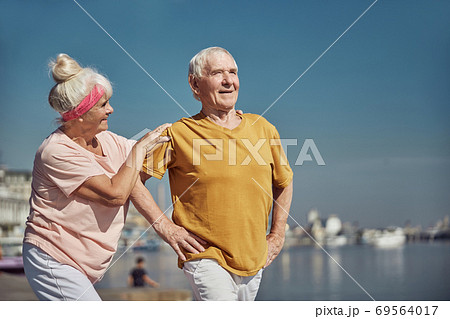 Male pensioner exercising along with his wife Male pensioner exercising along with his wife 69564017