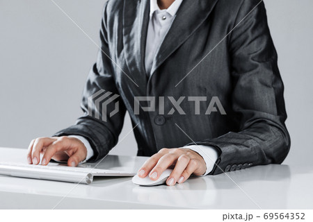 Closeup of businesswoman hand typing on keyboard with mouse on wood table 69564352