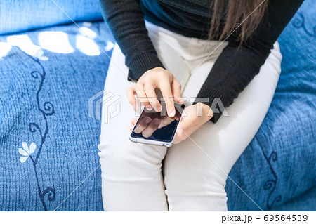 ソファーでスマホを操作する女性 ソファーでスマホを操作する女性 69564539