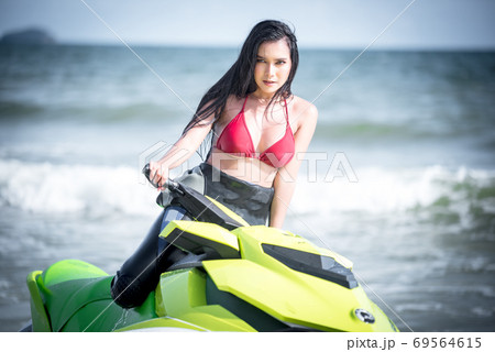 Asian female in bikini sitting on jet ski. 69564615
