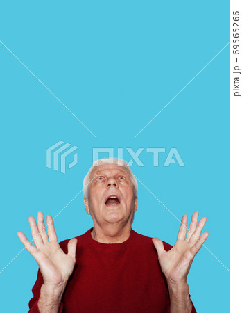 Elderly man with expression of amazement on blue background Elderly man with expression of amazement on blue background 69565266