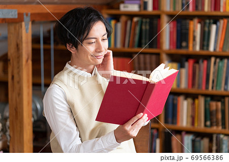 読書の秋 屋根裏部屋で本を読む笑顔の文学青年の写真素材