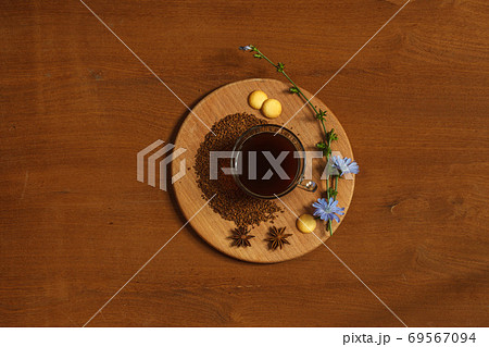 Hot drink made from ground chicory root, chicory granules and flowers on a wooden tray. Overhead, wooden background with space Hot drink made from ground chicory root, chicory granules and flowers on a wooden tray. Overhead, wooden background with space 69567094