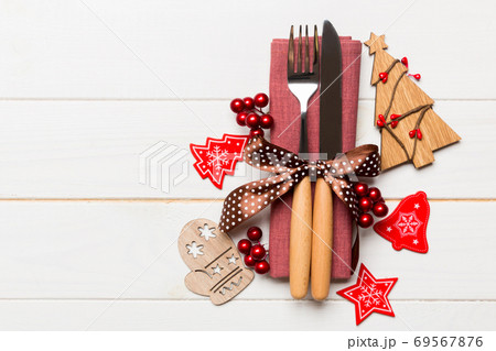 Top view of fork and knife tied up with ribbon on napkin on wooden background. Christmas decorations and New Year tree. Happy holiday concept with empty space for your design 69567876