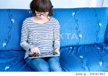 リビングでタブレットPCを操作する女性 リビングでタブレットPCを操作する女性 69567962