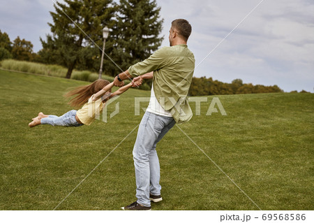 Young loving father playing and having fun with his cute little daughter while visiting beautiful green park on a warm summer day 69568586