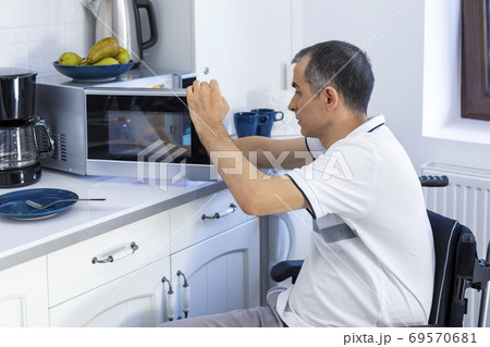 Disabled Man Using Microwave Oven For Baking In Kitchen Disabled Man Using Microwave Oven For Baking In Kitchen 69570681