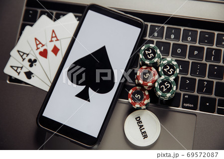 Online poker casino theme. Gambling chips, smartphone and playing cards on laptop keyboard Online poker casino theme. Gambling chips, smartphone and playing cards on laptop keyboard 69572087