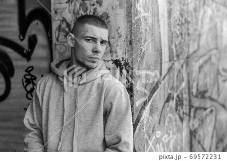 A bully guy in a light sports jacket with a hood. Black and white photo. BW A bully guy in a light sports jacket with a hood. Black and white photo. BW 69572231