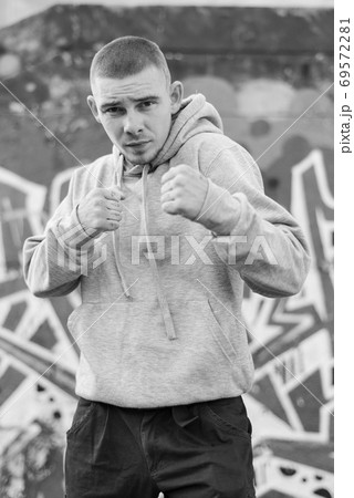A bully guy in a light sports jacket with a hood. Black and white photo. BW A bully guy in a light sports jacket with a hood. Black and white photo. BW 69572281