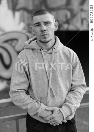 A bully guy in a light sports jacket with a hood. Black and white photo. BW 69572282