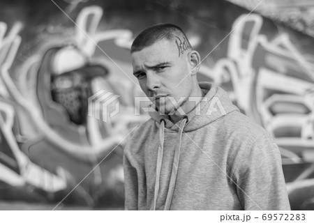 A bully guy in a light sports jacket with a hood. Black and white photo. BW A bully guy in a light sports jacket with a hood. Black and white photo. BW 69572283