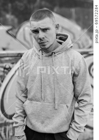 A bully guy in a light sports jacket with a hood. Black and white photo. BW A bully guy in a light sports jacket with a hood. Black and white photo. BW 69572284