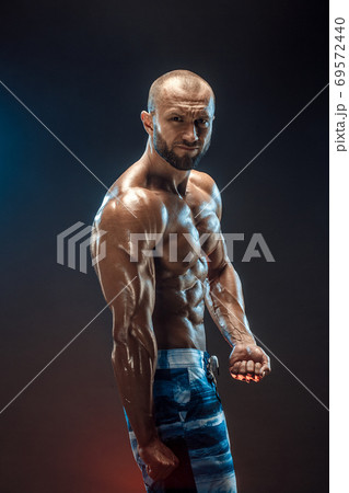 Handsome strong bodybuilder posing in studio on black background 69572440