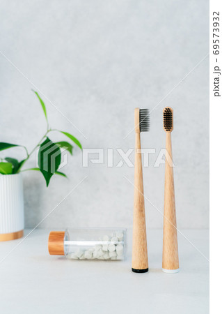 Zero waste bathroom items. Bamboo toothbrushes in recycling material holder, natural mouthwashing tabs and fresh green plants in glass. Oral care essentials. Eco-friendly home. Minimalism. Copy space. 69573932