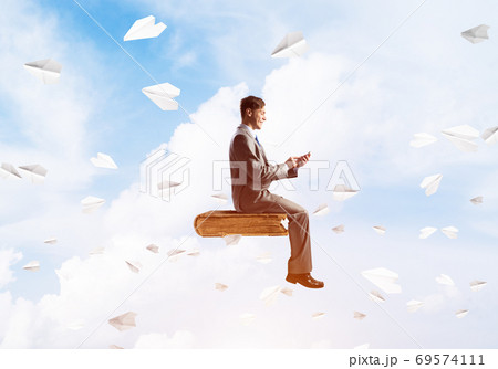 Businessman or student on book and paper planes flying around Businessman or student on book and paper planes flying around 69574111