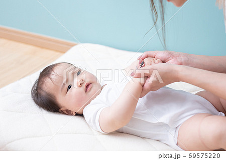 赤ちゃんを床に寝かせる女性 69575220