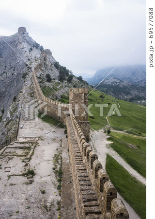 The wall that runs along the ridge of the mountain and the towers of Genoese fortress of the 14th century in the Sudak bay on the Peninsula of Crimea 69577088