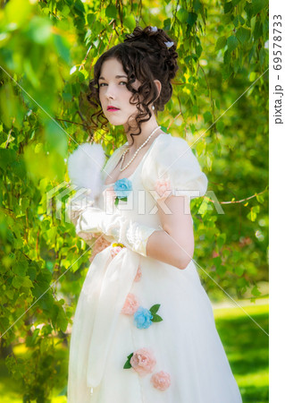 Beautiful woman in a dress of the bride with a fan in park 69578733