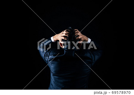 黒バックで頭をかかえるビジネスマン 69578970