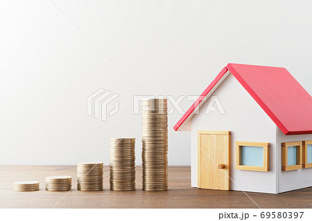 お金と家のミニチュア。住宅に関する金融と投資のイメージ。木のテーブルの上のミニチュアの家と積み上げた お金と家のミニチュア。住宅に関する金融と投資のイメージ。木のテーブルの上のミニチュアの家と積み上げた 69580397