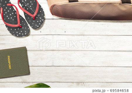 Top view of passport, slipper, and luggage bag with wooden background Top view of passport, slipper, and luggage bag with wooden background 69584658